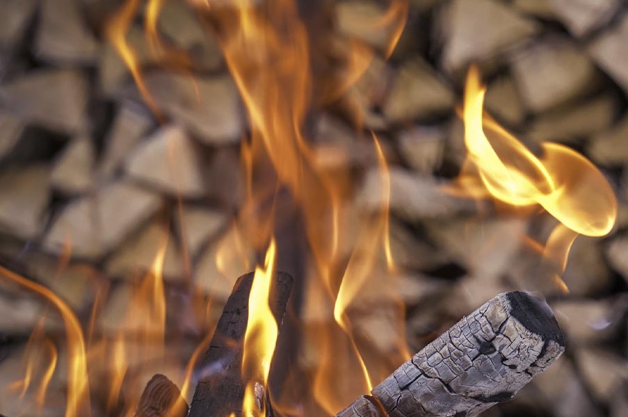 Close-up of dancing flames over burning logs, representing transformation, passion, and the Fire element in tantric breathing exercises.