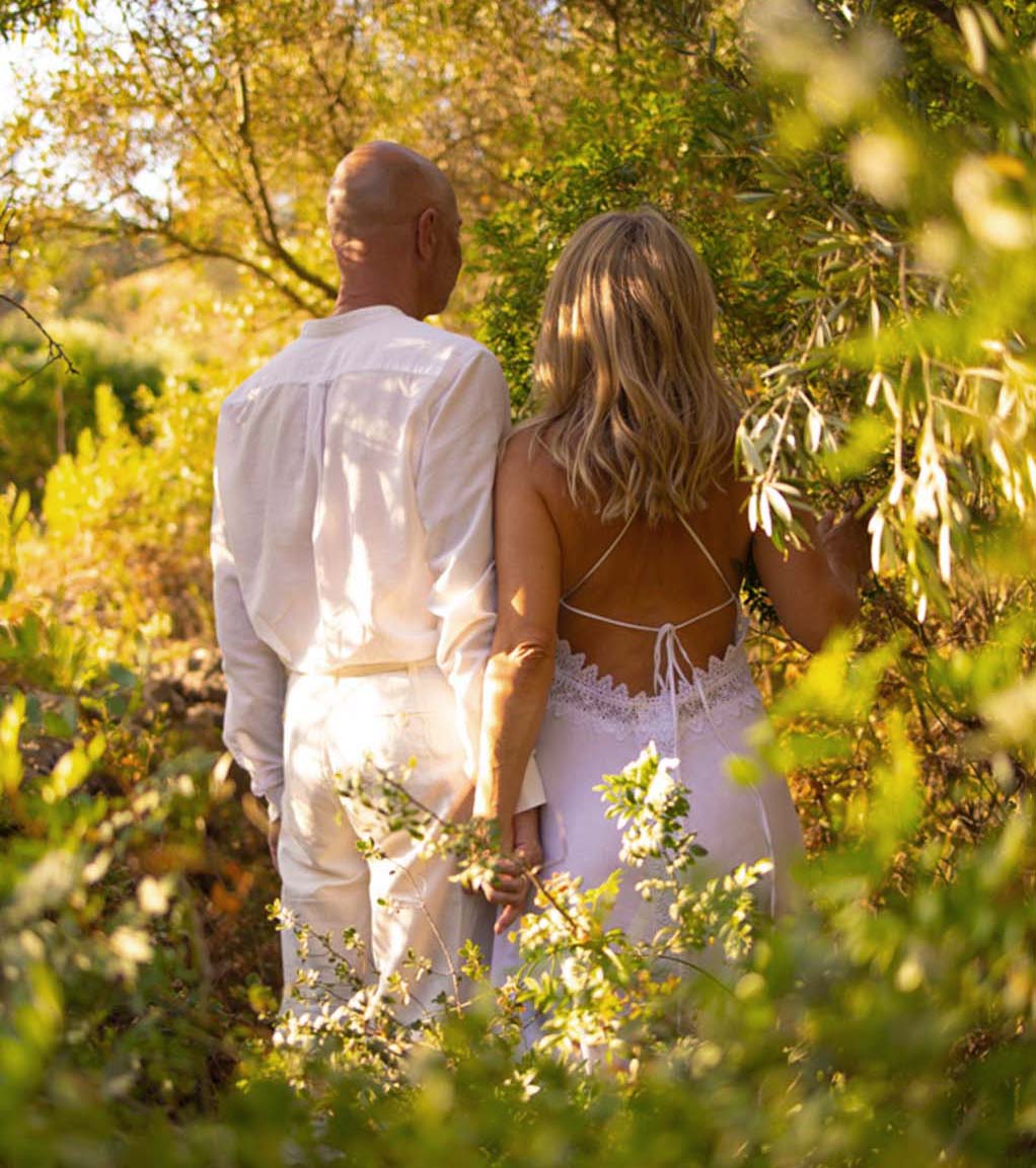 Monica and Peter of Connective Tantra School sitting in nature, forehead to forehead with hands in prayer, practicing tantric communication and presence.